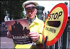 Crossing guard John Rooney looked over the agreement while waiting for children in Belfast yesterday. (Globe Staff Photo / Frank O'Brien)